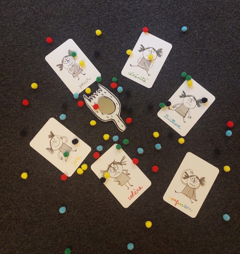 Atelier sur les émotions : cartes et pompons colorés autour d'un miroir