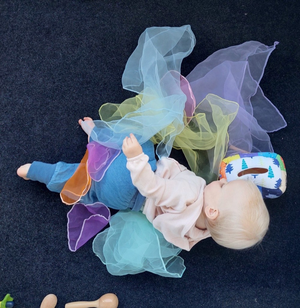 Bébé en séance de psychomotricité, explorant des foulards colorés